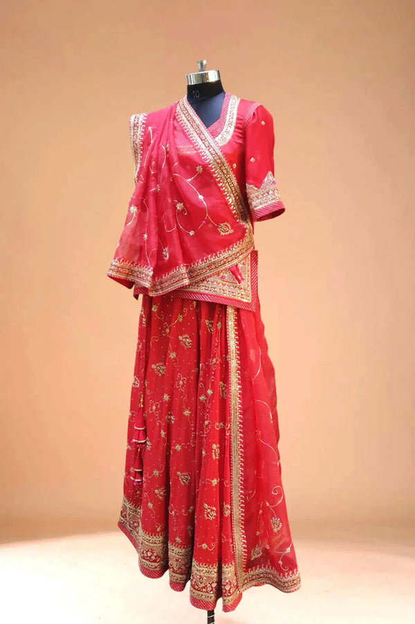 Red embroidered lehenga with gold detailing and dupatta on mannequin, ethnic Indian dress
