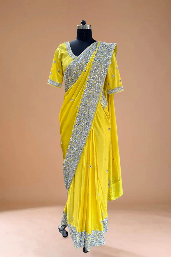 Yellow designer saree with intricate silver embroidery, displayed on a mannequin against a plain background