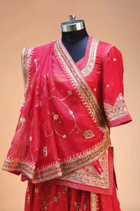Red Indian lehenga choli with gold embroidery and dupatta on a mannequin