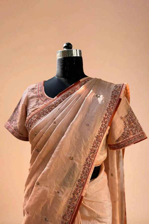 Peach hand-embroidered saree with floral border and blouse on mannequin