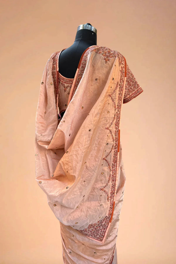 Peach embroidered saree with sequin details displayed on mannequin