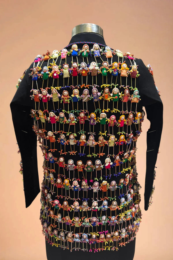Black blazer with colorful handmade doll embellishments on the back, displayed on mannequin