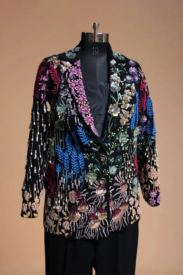 Black blazer with colorful floral embroidery, displayed on mannequin against neutral background