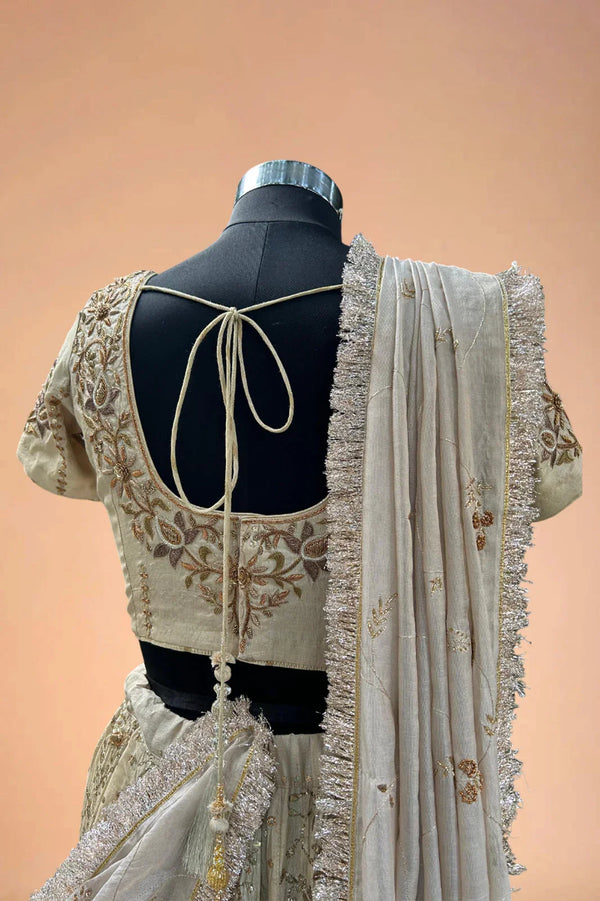 Back view of embroidered beige lehenga blouse with tie-up detail and sequin dupatta