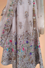 Luxury Indian designer dress with beige base, intricate floral embroidery, and gold tassels