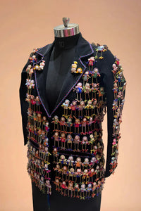 Black blazer adorned with colorful handcrafted doll embellishments on a mannequin.