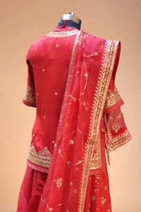Back view of a red Indian designer lehenga with gold embroidery and net dupatta
