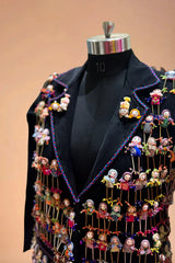 Black designer blazer decorated with colorful handcrafted dolls on a dress form