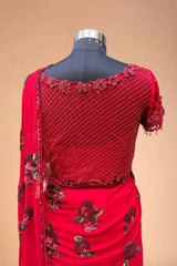 Red designer saree blouse with floral embroidery and net detailing on a mannequin