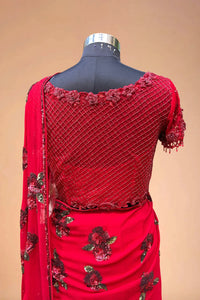 Red designer saree blouse with floral embroidery and net detailing on a mannequin