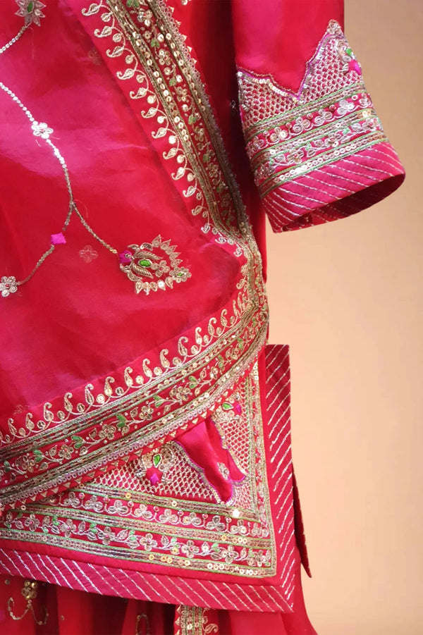 Red Indian ethnic dress with intricate gold embroidery and sequin details on silk fabric