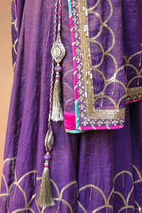 Close-up of purple Indian ethnic dress with gold embroidery and tassel accents