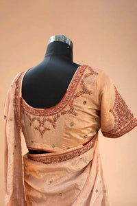 Peach silk saree with floral embroidery and matching blouse on mannequin