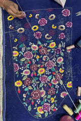Hand embroidery of colorful floral patterns on navy blue fabric for luxury Indian ethnic wear