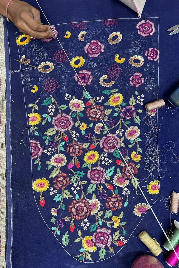 Hand embroidery of colorful floral patterns on navy blue fabric for luxury Indian ethnic wear