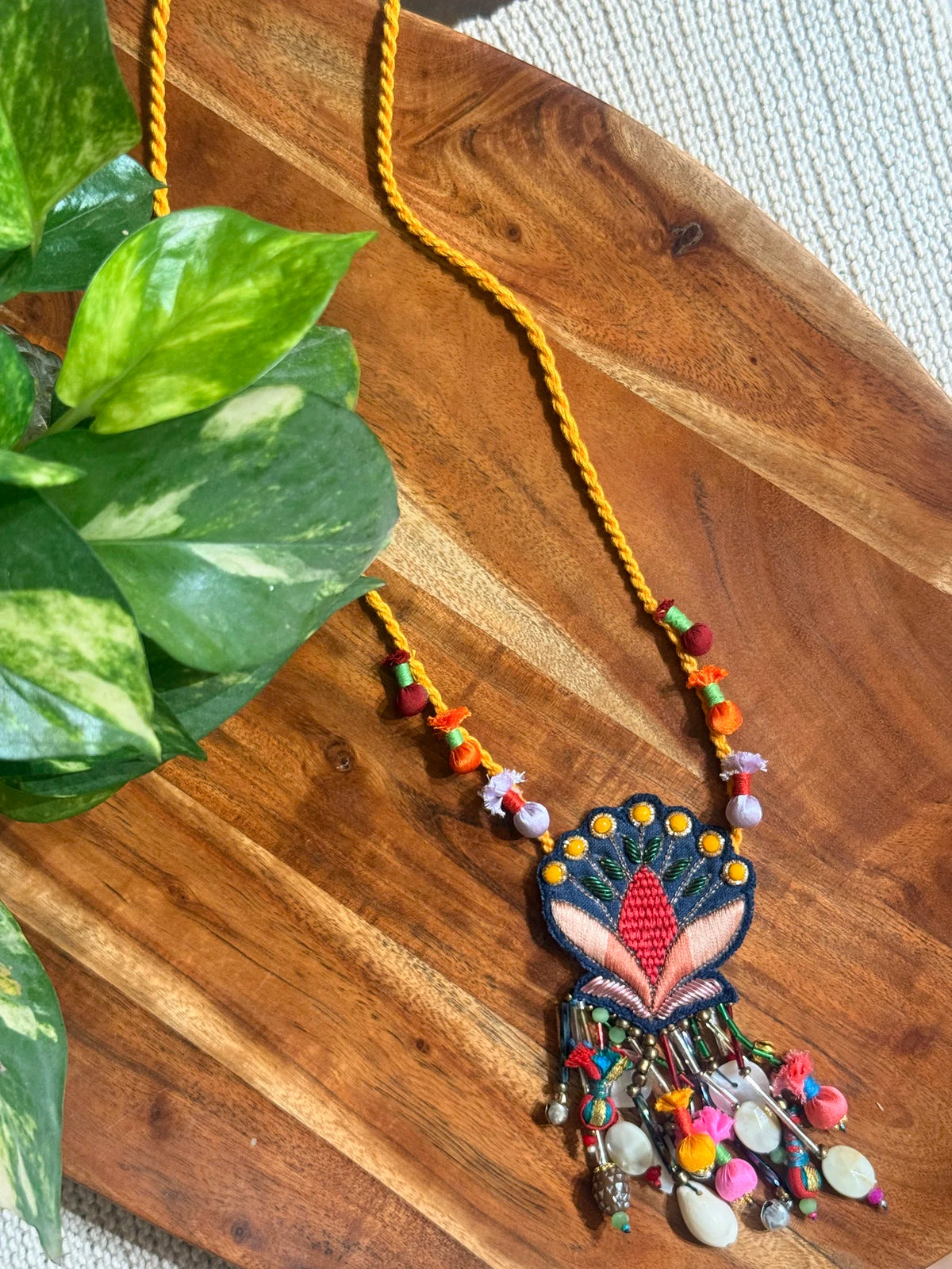 Nisha handcrafted textile necklace floral pendant on a wooden surface | Utsavi by Shilpa