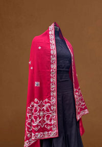 Red embroidered pashmina shawl with intricate floral patterns draped over a black dress