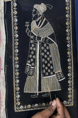 Hand embroidery on black shawl featuring regal figure with gold floral patterns