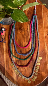 Vinyas handcrafted textile necklace coloured strands laid on a wooden surface | Utsavi by Shilpa