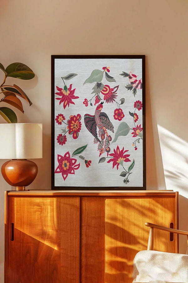 Framed wall art with colorful bird and floral design above wooden cabinet in modern living room