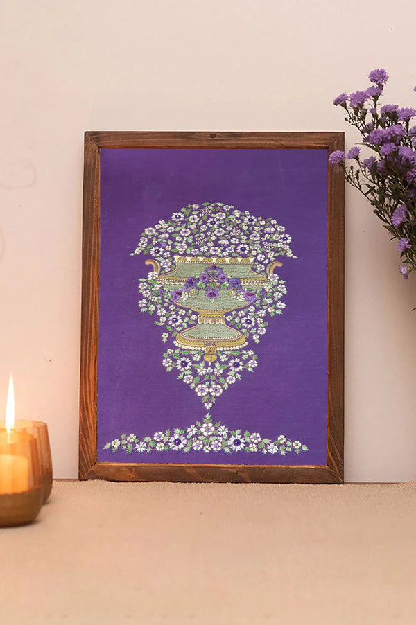 Floral wall art with a vase design on a purple background, framed in wood, with candle and flowers