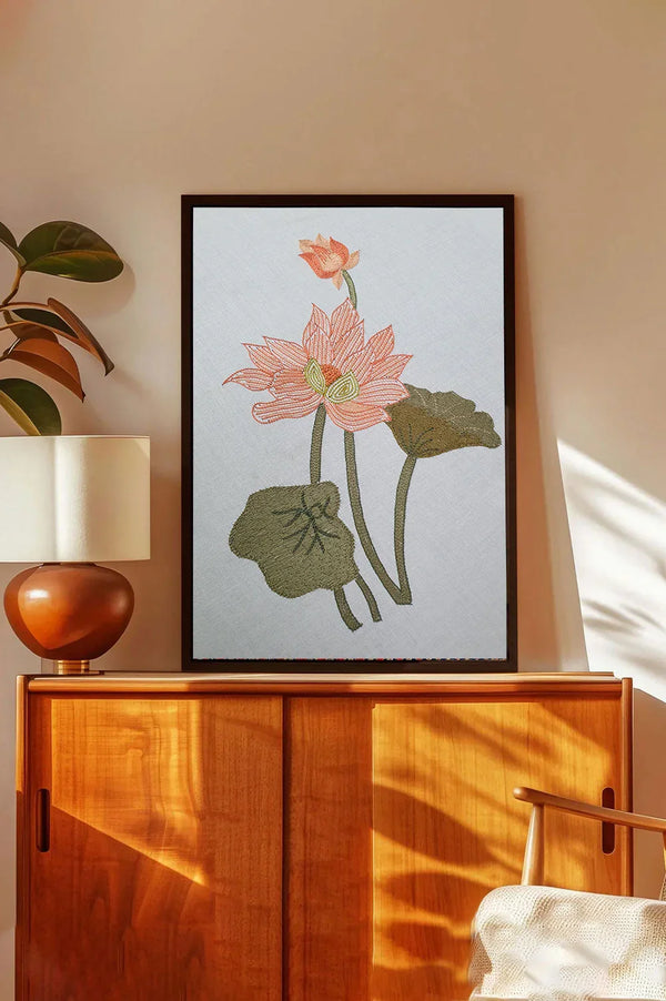 Framed lotus flower embroidered wall art above a wooden cabinet in a modern living room