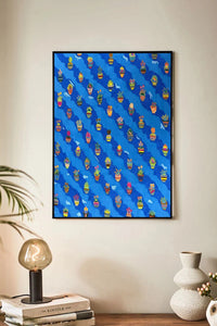 Framed artwork with a blue background and colorful pattern on a wall above a shelf.
